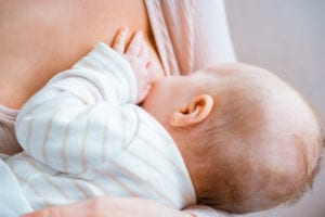 close-up partial view of young mother breastfeeding infant baby