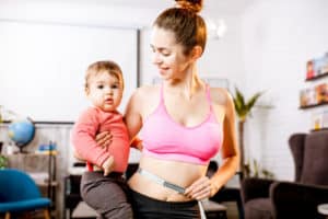 Young mother in sportswear measuring her waist worried about her weight after the child birth 