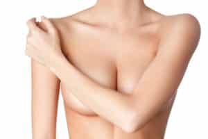 A woman covering her breasts with her arm after breast implant removal