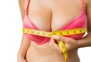A woman considering breast reduction surgery with a tape measure wrapped around her breasts