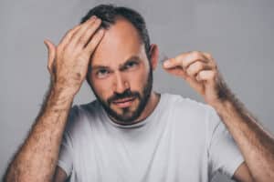 A man dealing with stress-related hair loss holding his hair