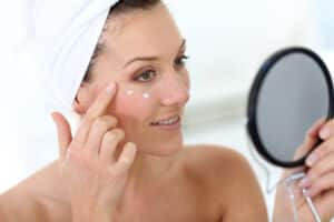 A woman looking in the mirror and applying SkinMedica® skincare products in Palm Springs