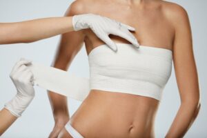 A surgeon wrapping a woman's breasts after breast implant removal in Palm Springs